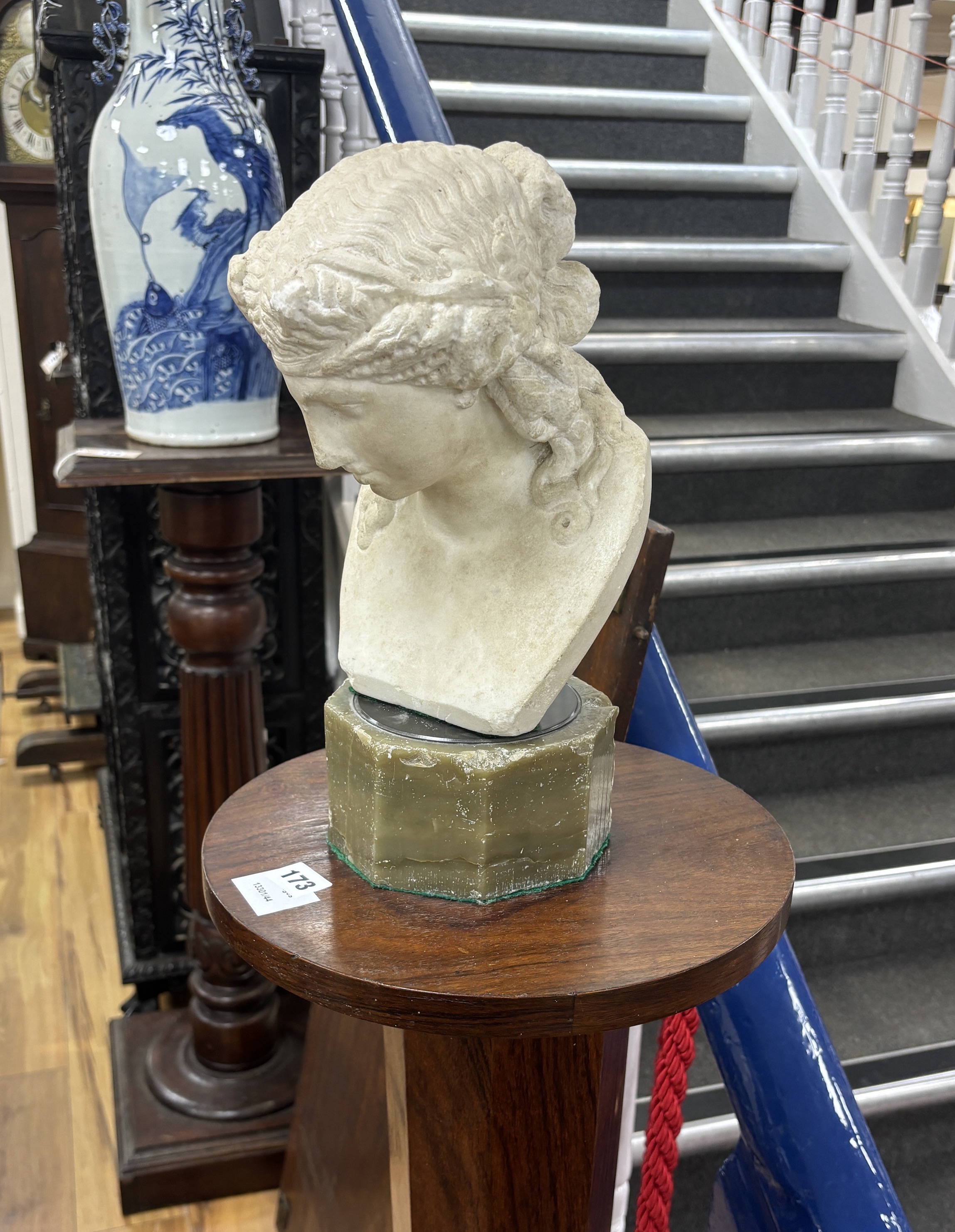After the Antique, a carved marble bust of a young woman on octagonal onyx plinth and rosewood pedestal, combined height 142cm